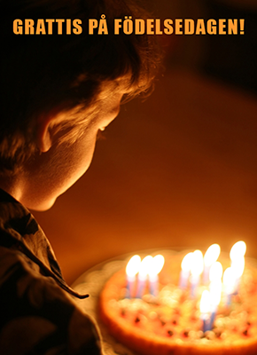 Ett barn i ett mörkt rum med en tårta full av ljus, beredd att blåsa ut ljusen och texten grattis på födelsedagen.